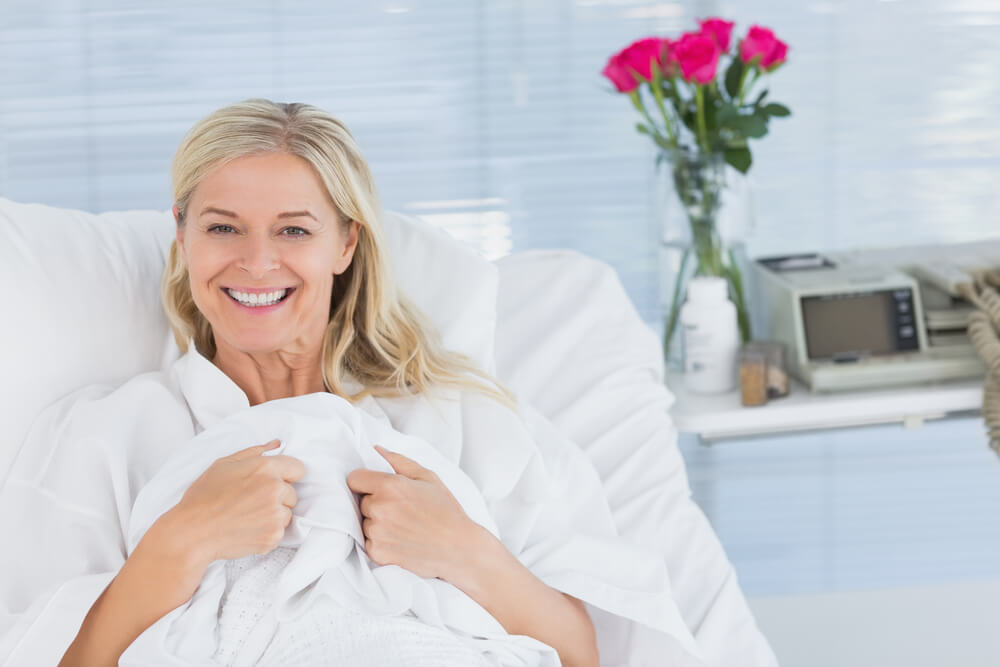 Smiling Patient Looking at Camera on Her Bed in Hospital