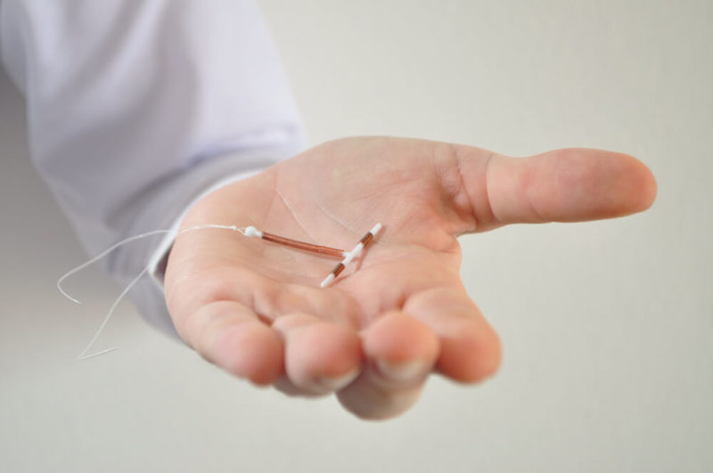 Holding an Iud Birth Control Copper Coil Device in Hand, Used for Contraception - Front View