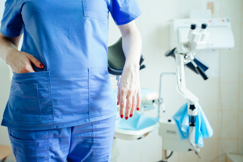 Woman Standing Next to a Chair in Gynecological Room