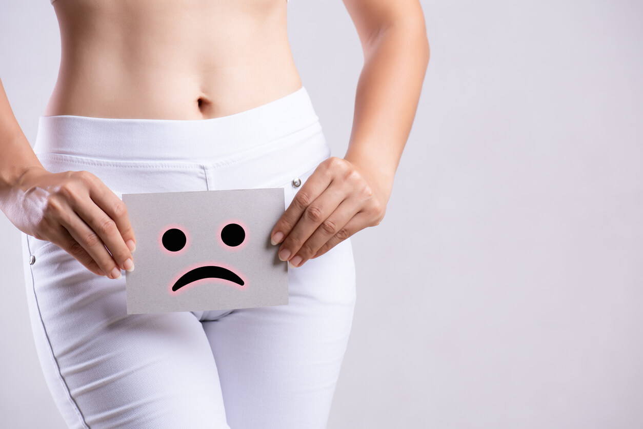 Closeup Young Woman Holding Paper With Sad Smiley Face or Unhappy Near Her Crotch Lower Abdomen.