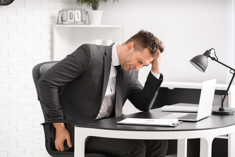 Young Man Suffering From Hemorrhoids in Office