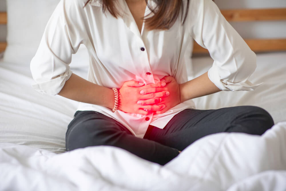 Woman Having Bladder Pain Problem Sitting on Bed in Bedroom