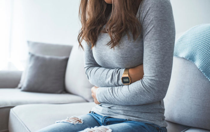 Beautiful Young Woman Lying on Bed and Holding Hands on Her Stomach.