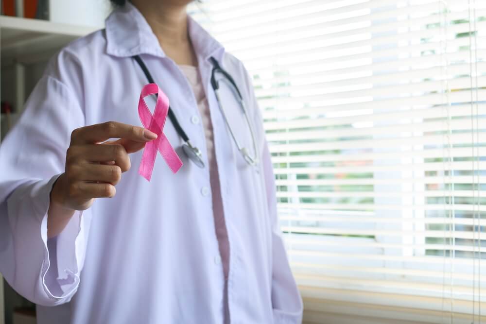 Portrait of Doctor in White Uniform Showing Pink Ribbon. Breast Cancer Awareness Ribbon