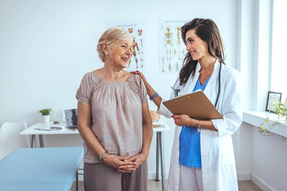 Portrait of Female Doctor Explaining Diagnosis to Her Patient. Female Doctor Meeting With Patient in Exam Room