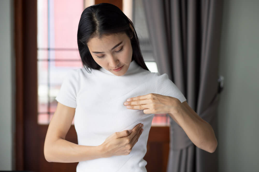 A woman checking her breast at home, concept of breast cancer awareness month, breast cyst or tumor inspection, body care, precautionary and preventive medicine
