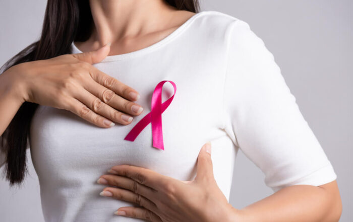 Closeup of pink badge ribbon on woman chest to support breast cancer cause.