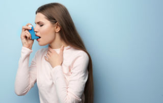 Young Woman Using Asthma Inhaler