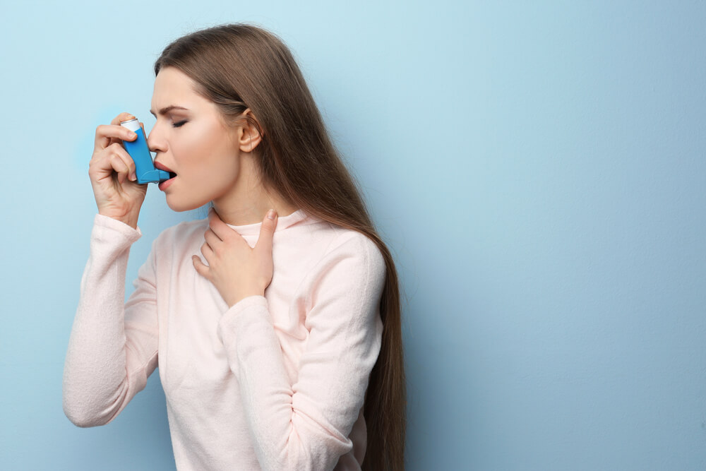 Young Woman Using Asthma Inhaler