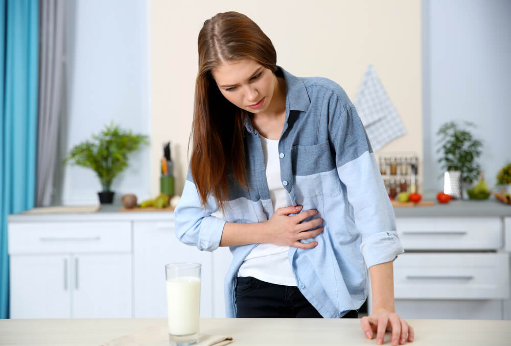 Woman With Dairy Allergy and Glass of Milk on Table