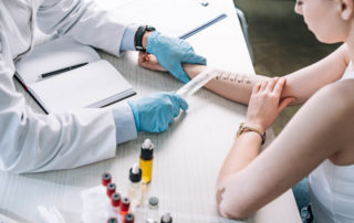 Overhead View of Allergist Holding Ruler Near Marked Hand of Woman