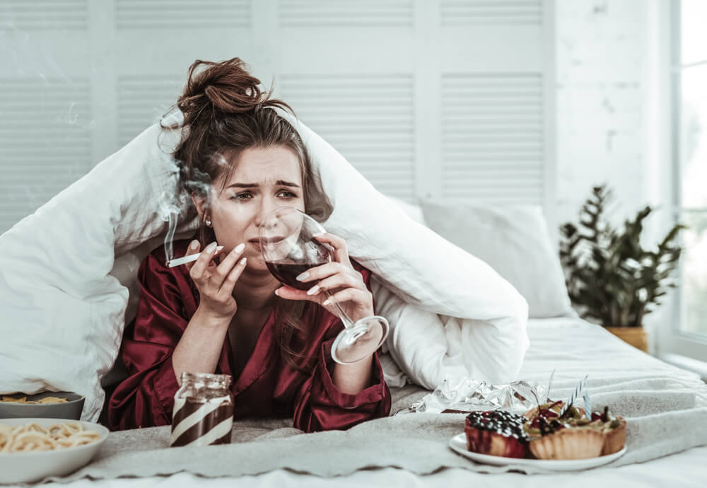 A Depressed Woman Smoking in the Bed and Drinking Wine