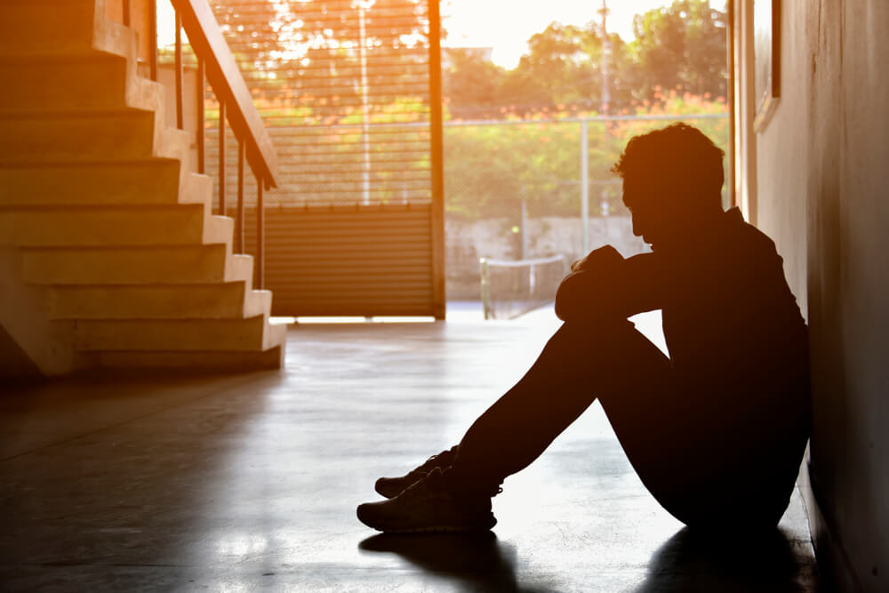 Silhouette of Sad Depressed Insomnia Man Sitting Against Sunset.