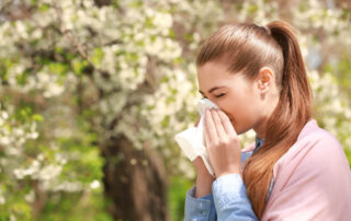 Sneezing Young Girl With Nose Wiper Among Blooming Trees in Park