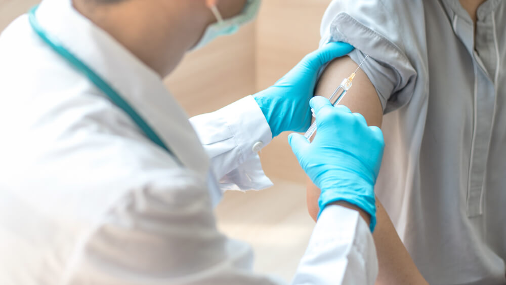 Teenager Woman Having Vaccination for Influenza or Flu Shot or HPV Prevention Vaccine With Syringe by Nurse or Medical Officer.