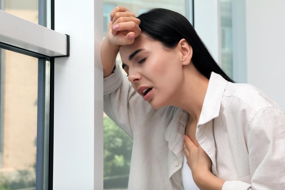 Young Woman Suffering From Breathing Problem Near Window Indoors