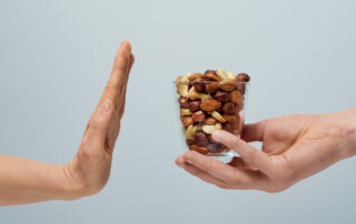 Allergy To Nuts. The Hand Shows A Stop To A Glass With Nuts.