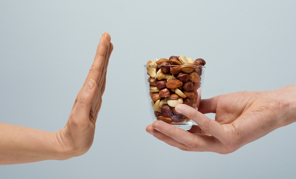 Allergy To Nuts. The Hand Shows A Stop To A Glass With Nuts.