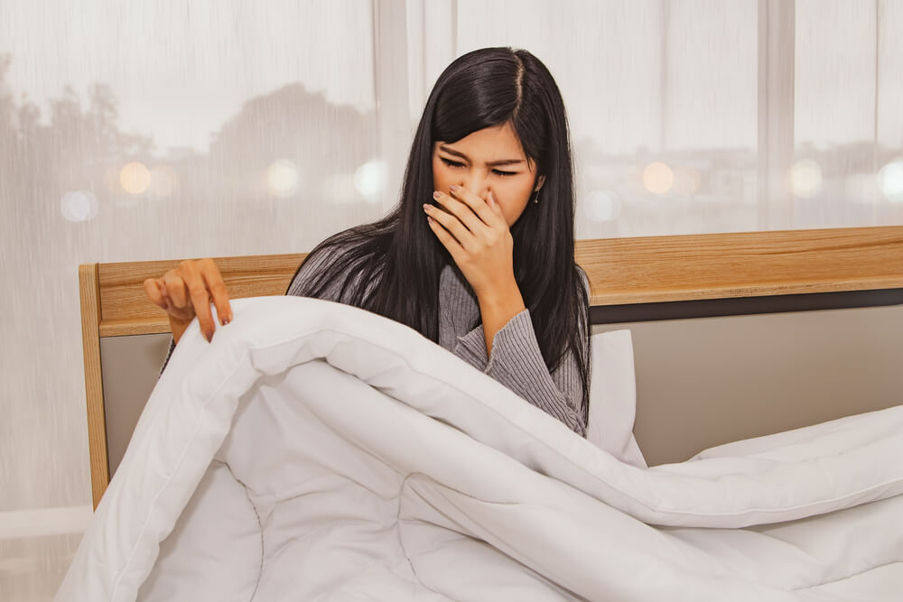 Concept respiratory health care and allergies: Woman has a stinging nose from a dirty blanket in her bedroom.