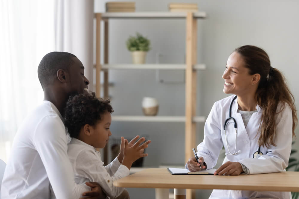 Smiling Pediatrician Doctor Consulting a Father With Child