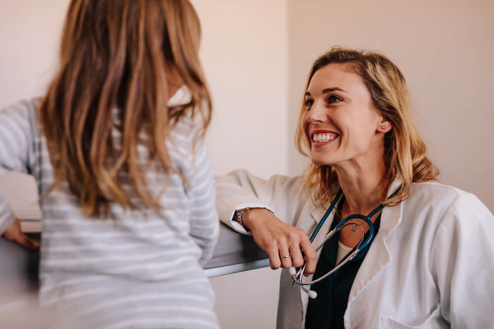 Friendly Happy Doctor Pediatrician With Patient Child Girl in Office at Clinic. Pediatrician and a Girl at Hospital.