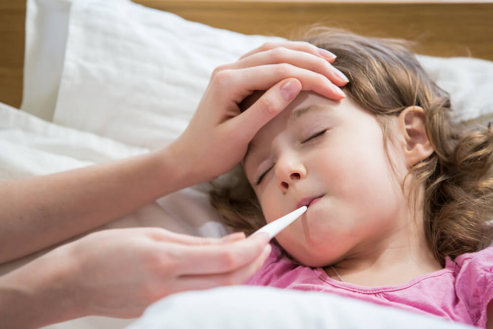  Sick Child With High Fever Laying in Bed and Mother Holding Thermometer. Hand on Forehead.