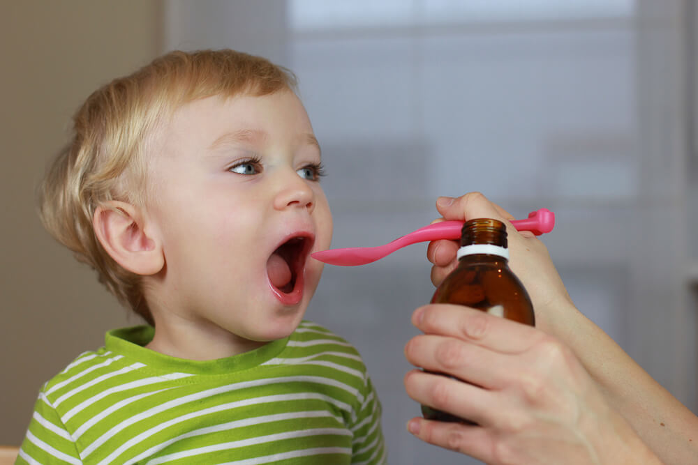 Mother Giving 2 Years Old Baby Boy Medicine, Cough Syrup on a Spoon