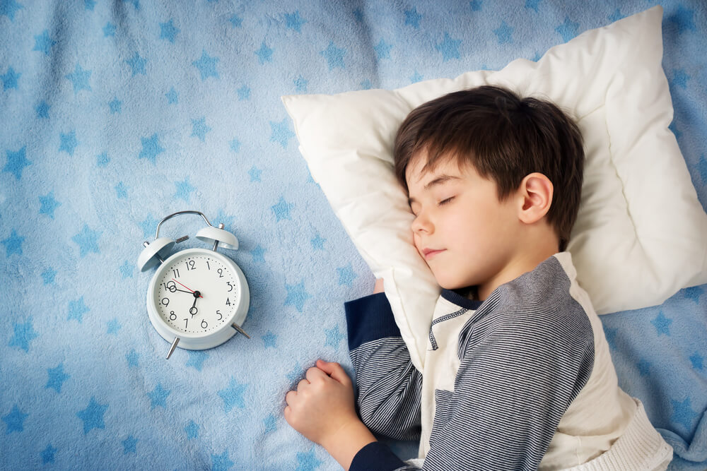 Six Years Old Child Sleeping in Bed With Alarm Clock