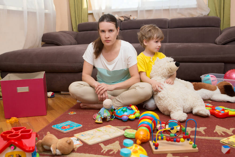 Young Pregnant Mother and Her Little Son, at Home. Mother and Little Son Sit On a Floor.