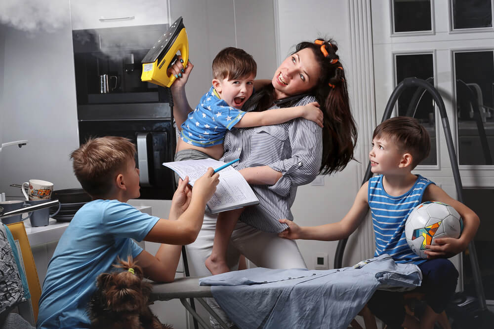 A Woman Irons and Spends Time With Her Children.