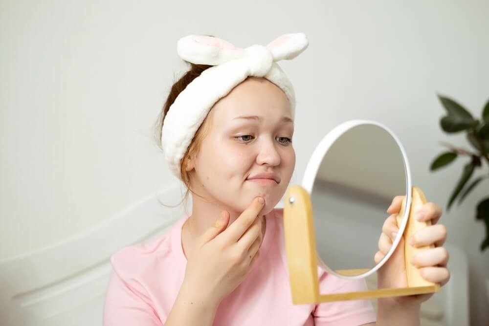 Frustrated Caucasian Teenage Girl Saw Pimple on Her Face in Mirror