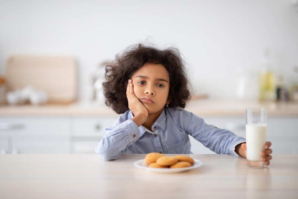 Portrait Of Sad Little Girl Holding Glass Of Milk