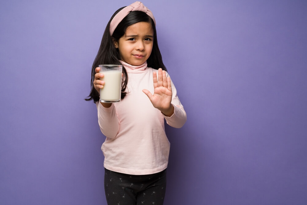 Upset Elementary Child With a Lactose Intolerance Refusing To Drink a Glass of Milk