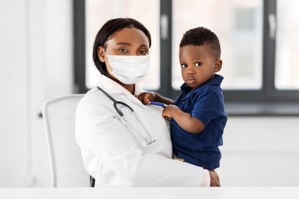 Pediatrician Wearing Protective Mask Holding Baby Boy Patient on Medical Exam at Clinic