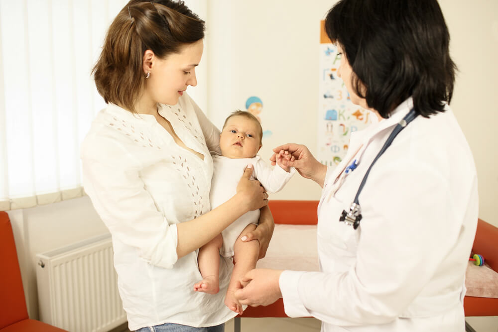 Doctor Looking at a Baby While Mother Is Holding It in Her Hands