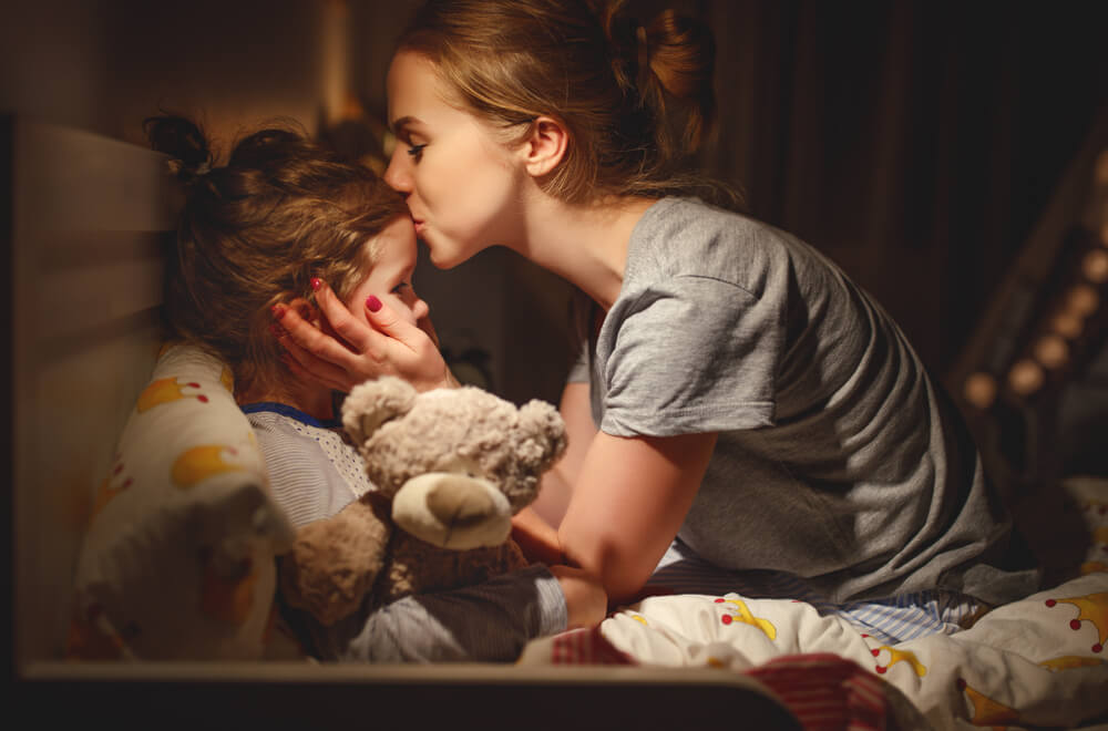 Mother Puts Her Daughter to Bed and Kisses Her in the Evening