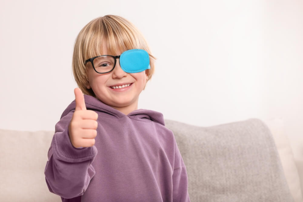 Happy Boy With Nozzle on Glasses for Treatment of Strabismus Showing Thumbs up in Room