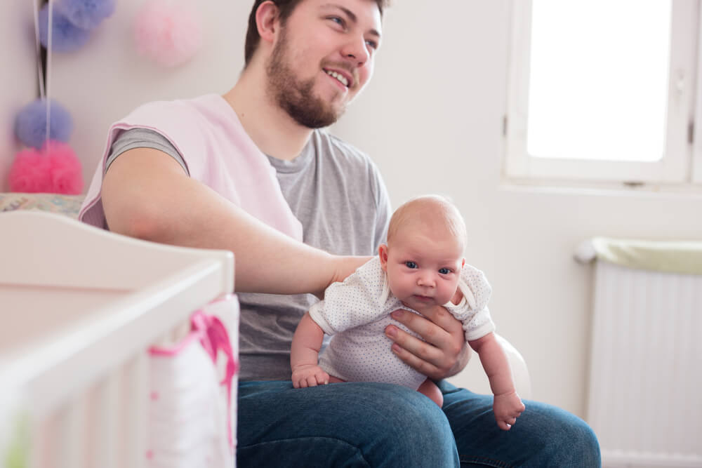 Young Father Burping His Newborn Daughter, Holding Her Affectionately. Lifestyle Shoot With Natural Light and Shallow Depth of Field.