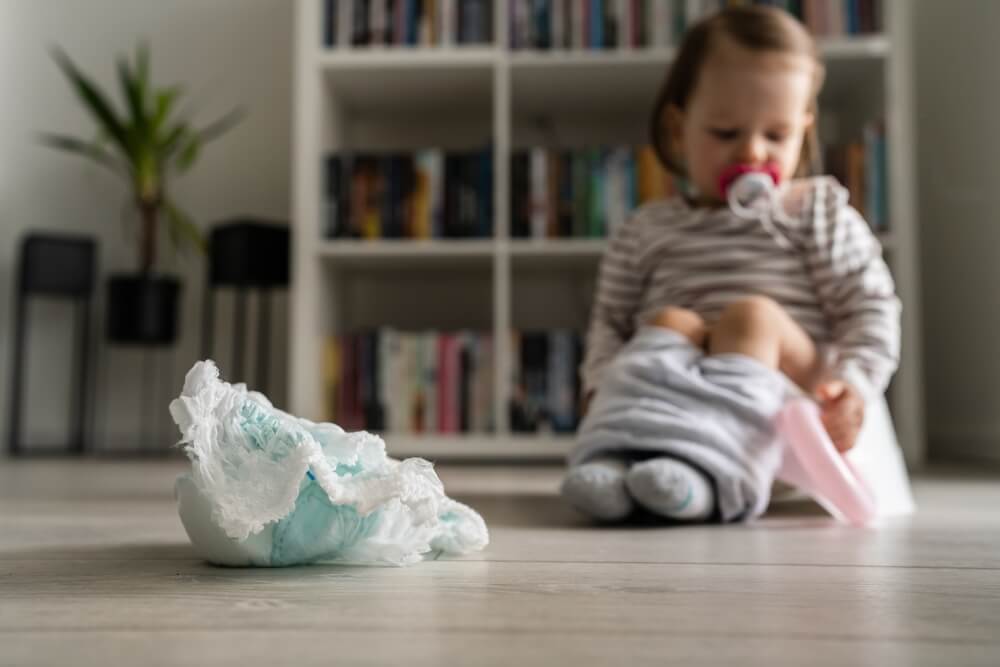 Baby Diapers Selective Focus With Small Child In Background Sitting On The Children's Potty At Home On The Floor