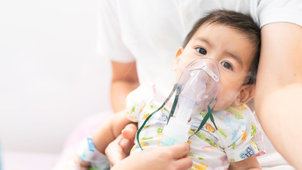 Close Up Of Asian Little Baby Boy Is Treated Respiratory Problem With Vapor Nebulizer To Relief Cough Symptom In The Hospital Room