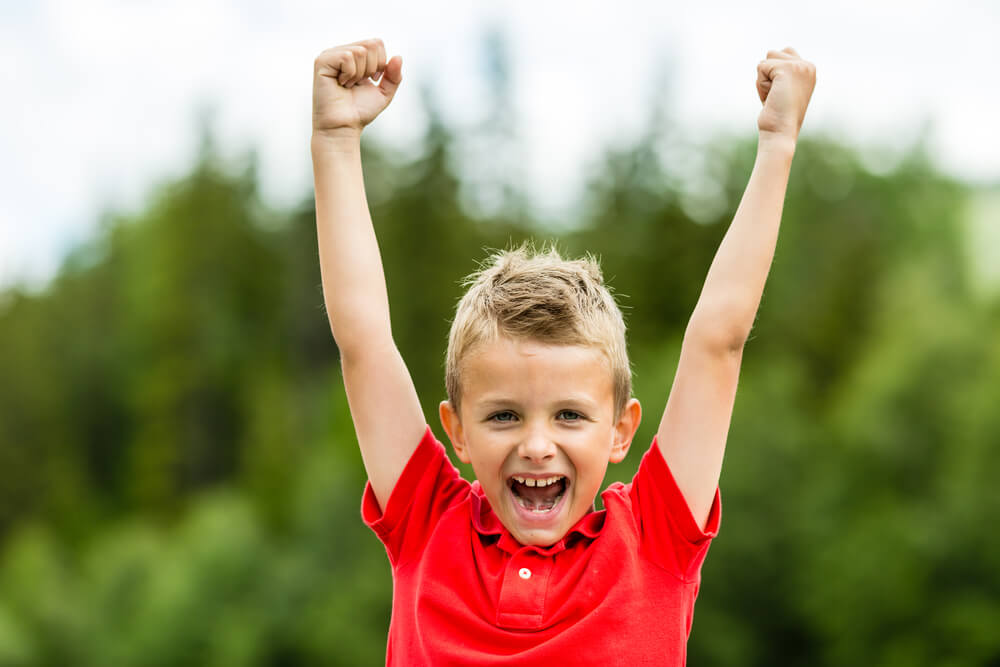 Self Confident Boy With Raised Fists Celebrating A Recent Success Or Victory.