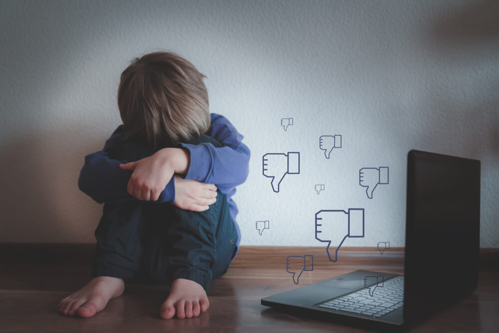 Cyber bullying concept - sad young boy with a notepad.