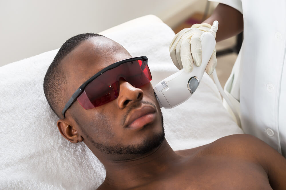 Close-up of Therapist Giving Laser Epilation Treatment on Young African Man