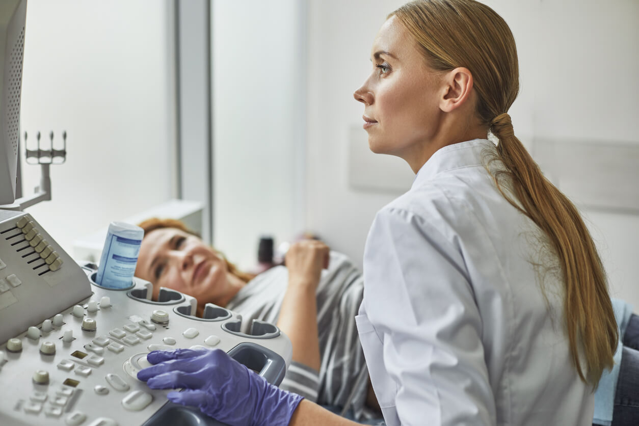 Side View Portraits of Gynecologist in White Lab Coat and Sterile Gloves Using Ultrasound Scanner While Examining Female Patient.
