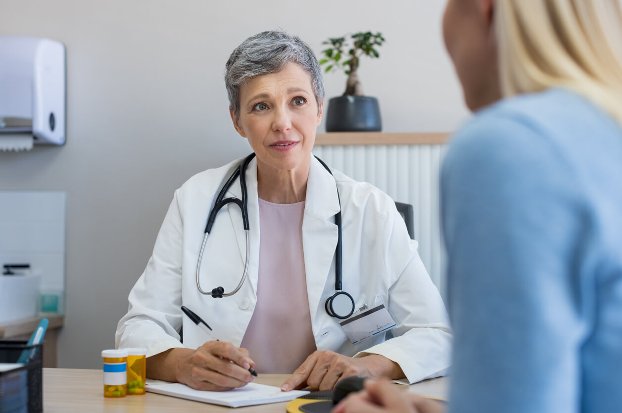 Mature Woman Doctor Consulting Patient in Hospital Room.