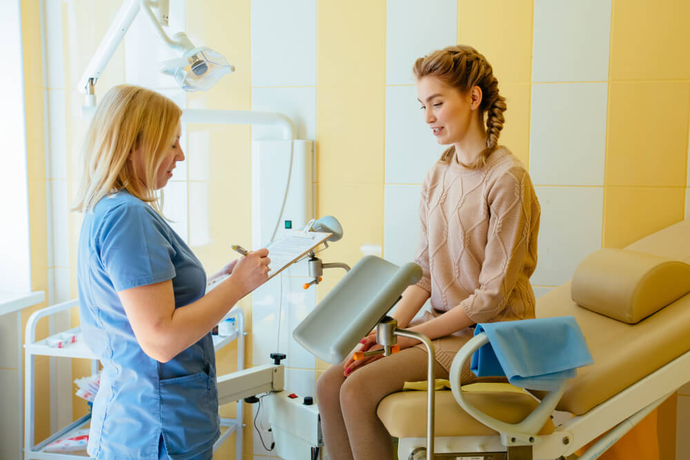 Gynecologist Consulting Happy Young Woman and Writing in Clipboard