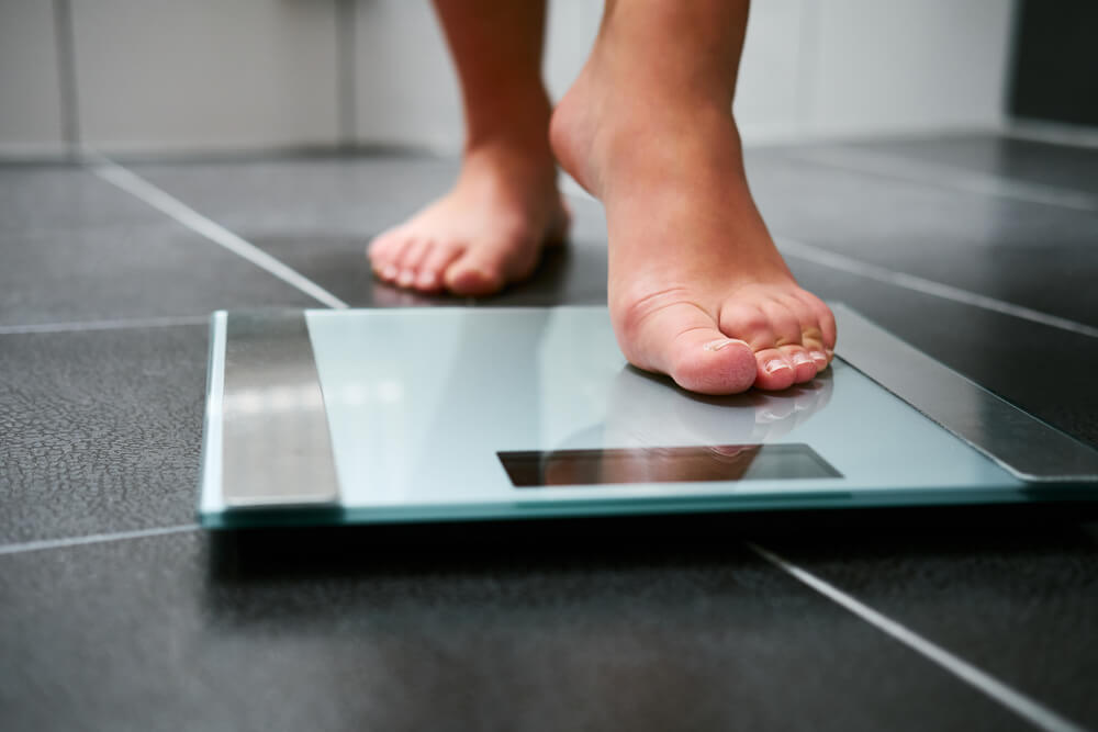 Female Bare Feet Standing on Weight Scale in the Bathroom