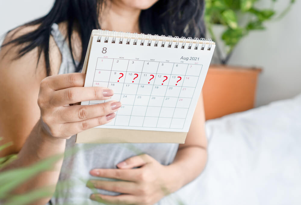 Woman Hand Holding Calendar With Question Mark Waiting for Late Blood Period