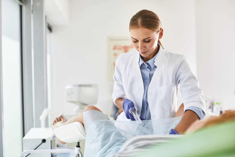 Gynecologist in White Lab Coat and Sterile Gloves Using Vaginal Speculum During Pelvic Exam