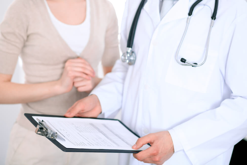 Close Up of a Male Doctor Holding an Application Form While Consulting Patient